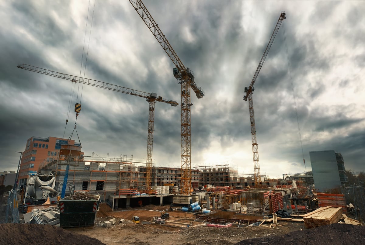 Construction cranes against a dramatic cloudy sky